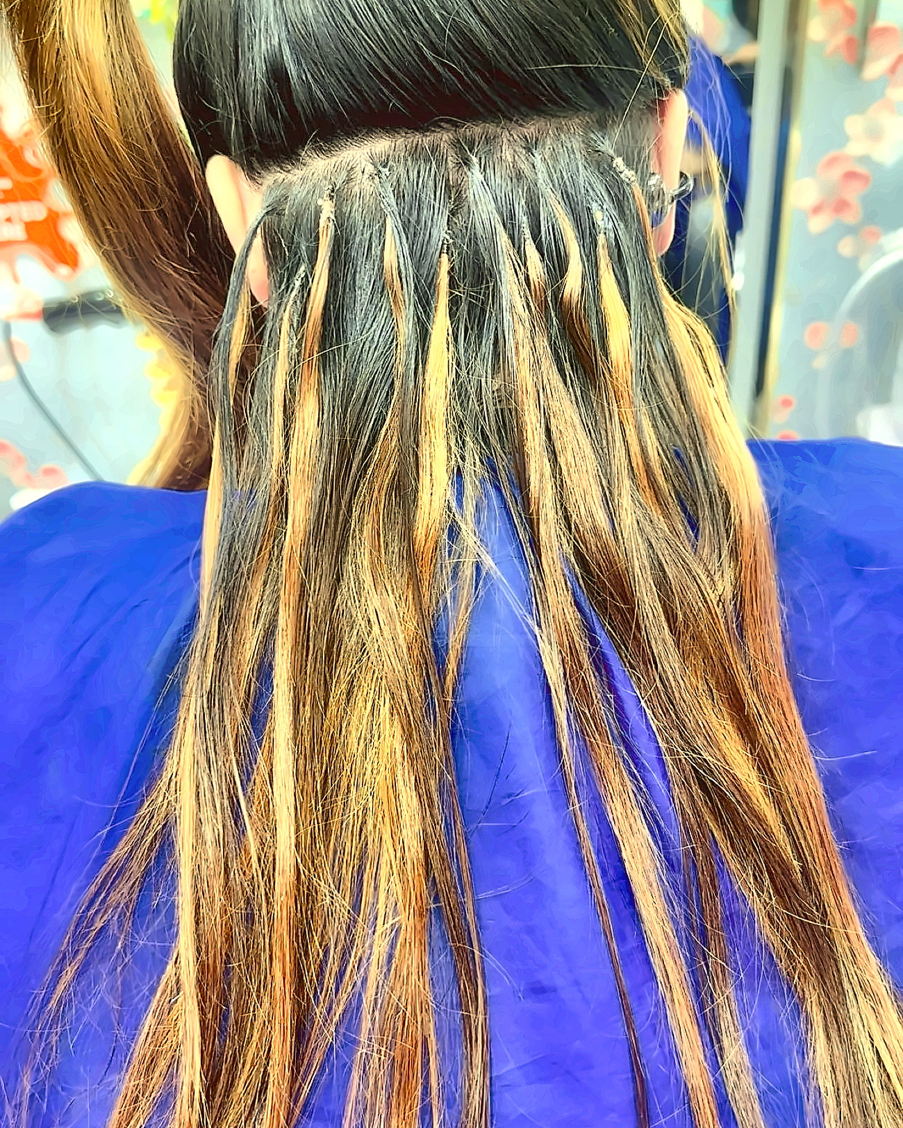 Caramel highlighted lengths blended into dark hair, sectioned over a salon cape