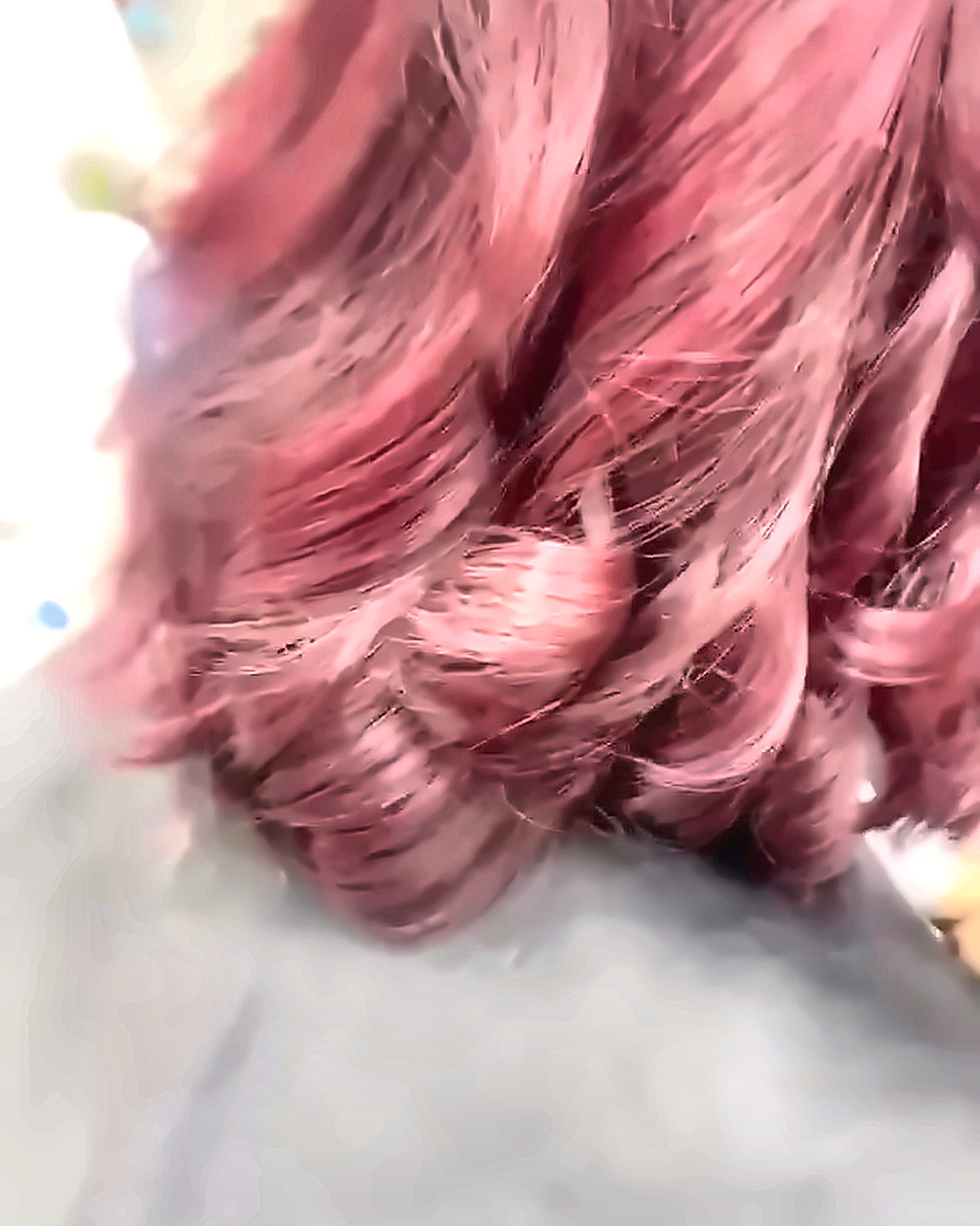 Hair freshly coloured in a deep rose-wine tone, sectioned and lifted to show the even coverage