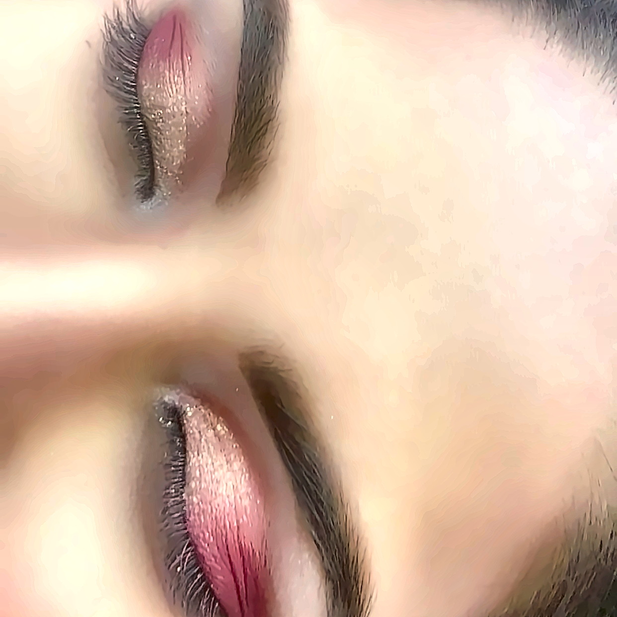 Close-up of both eyes with pink and silver glitter eyeshadow and freshly shaped brows